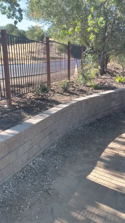 Curved block retaining wall below an iron fence