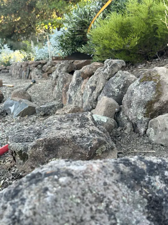 A boulder wall going up, seen from the ground