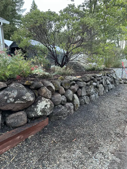 Dry-stacked boulder wall, with a timber edge to the gravel path